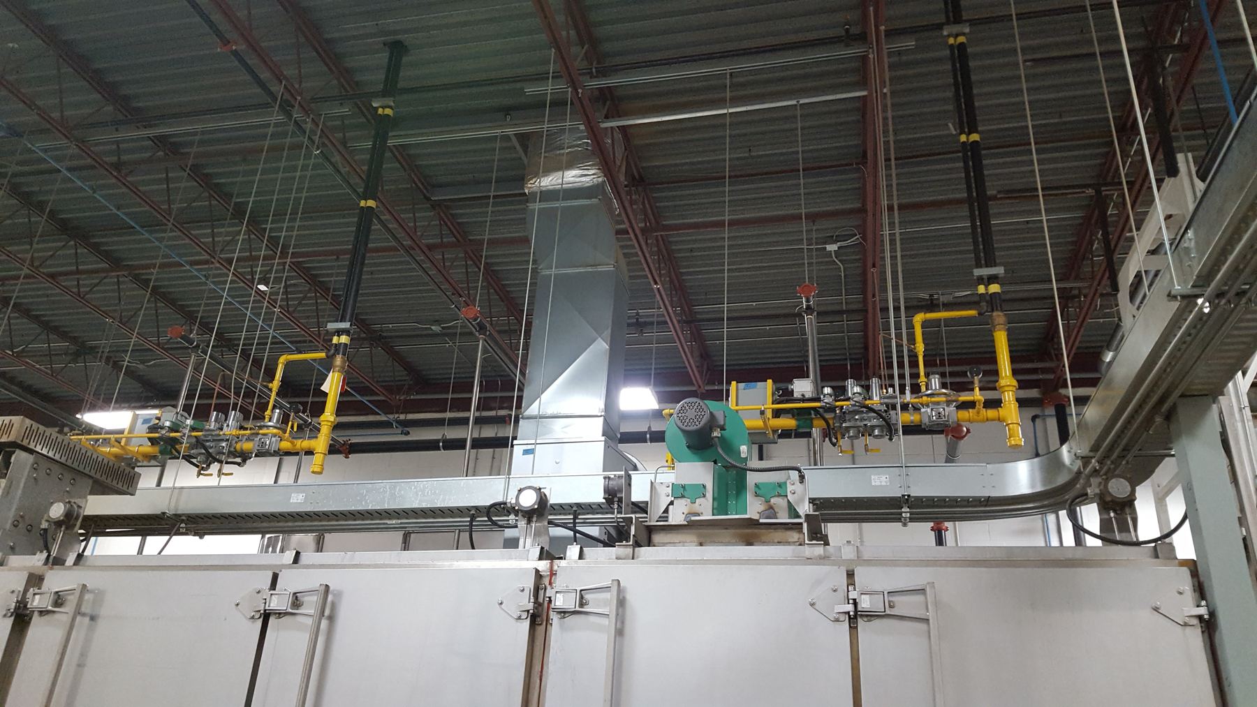 Yellow overhead gas piping feeding industrial ovens